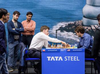 Jan-Krzysztof Duda spielt gerade 23. Tc7! gegen Samuel Shankland, die anderen Turnierteilnehmer staunen, darunter Parham Maghsoodloo (rechts am Bildrand)