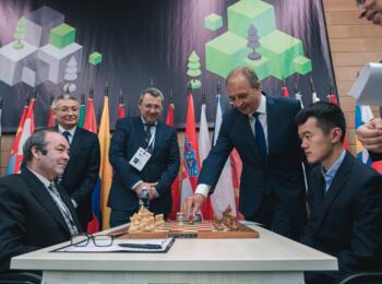 Symbolischer 1. Zug (mit Schwarz!) am Brett von Liren Ding (rechts) gegen Shaun Press (Papua Neuguinea), der Mitglied der FIDE-Regelkommission ist